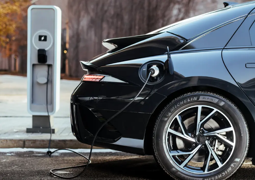 Un vehículo eléctrico negro se recarga con los neumáticos de invierno Michelin Alpin 7 montados, que mejoran la autonomía del vehículo eléctrico en condiciones de frío