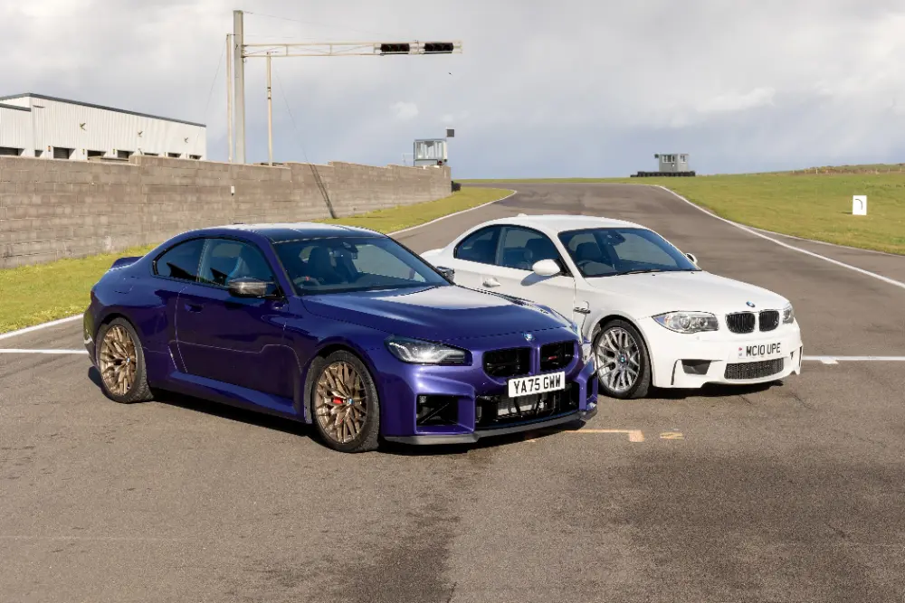 BMW M2 CS i blå-lila och BMW 1-serie M Coupé i vitt, i en direkt jämförelse på en racerbana