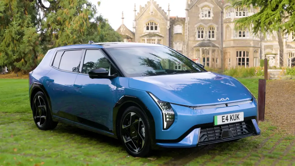 Kia EV4 hatchback 2026 albastru parcat în fața unei case de țară - mașină electrică compactă cu autonomie de 625 km