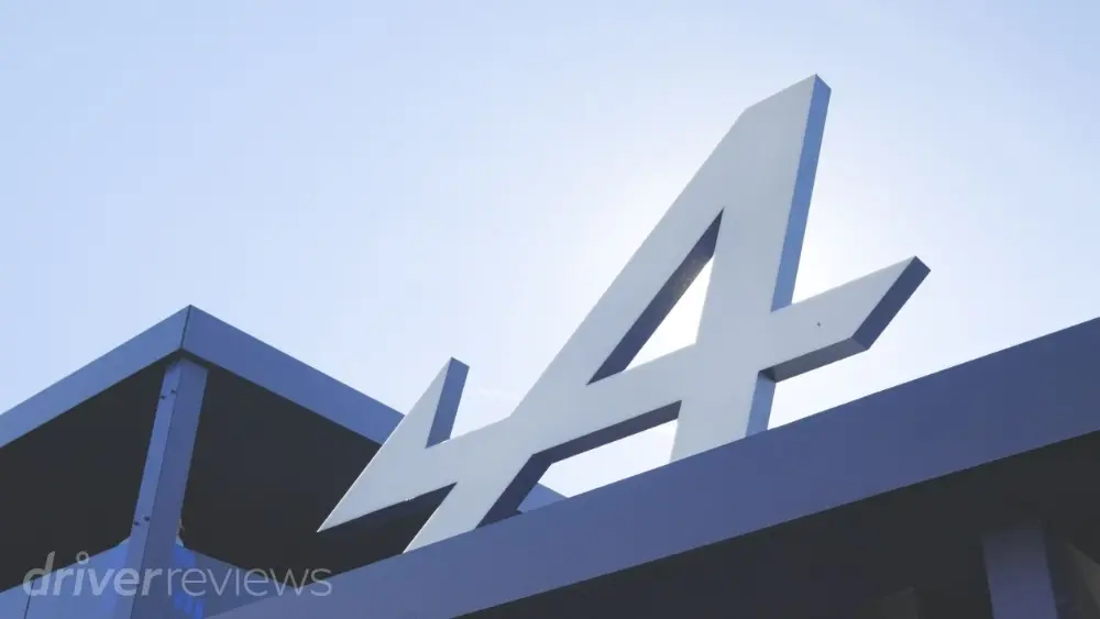 Logo Alpine montato sulla facciata di un edificio, fotografato sotto un cielo sereno.