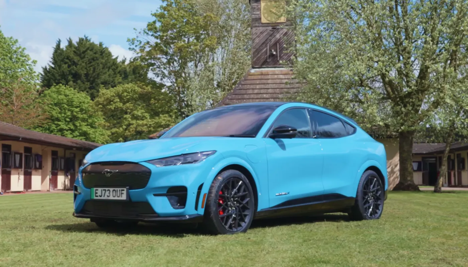 Der Ford Mustang Mach-E GT auf einem kleinen Feld geparkt als Teil eines Video-Drehs