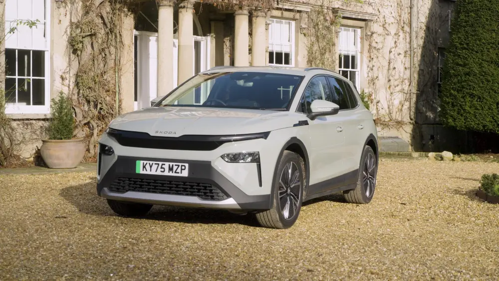 Skoda Elroq 85 in Hellgrau vor einem britischen Herrenhaus mit Efeu-bewachsener Fassade