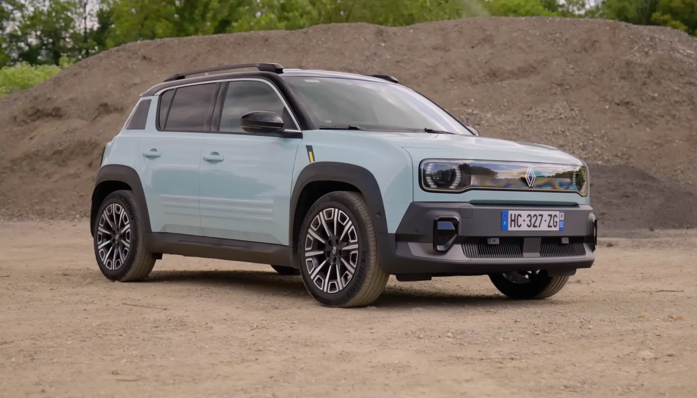Un SUV eléctrico verde delante de un montículo de tierra.
