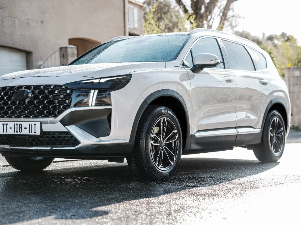 Hyundai Santa Fe i vitt, parkerad utomhus med synlig frontgrill och aluminiumfälgar.