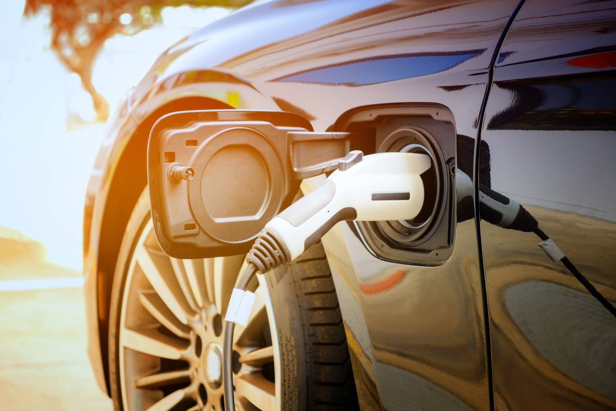 Un'auto elettrica viene ricaricata presso una stazione di ricarica; primo piano della presa di ricarica