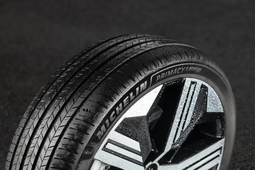 Michelin Primacy-däck monterat på en aluminiumfälg med geometriskt mönster, med synligt mönster mot en mörk bakgrund.