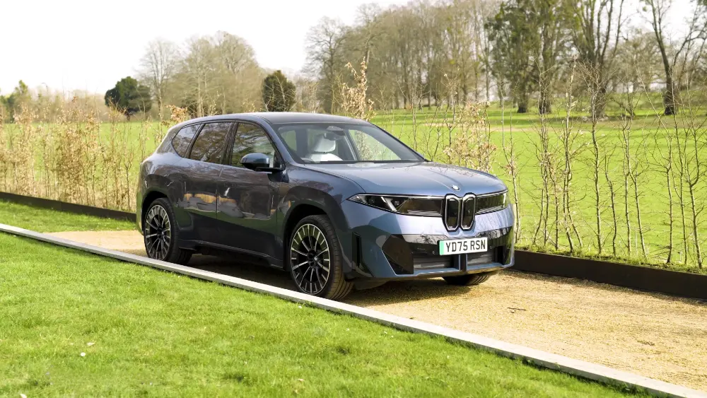 BMW iX3 50 xDrive, vista frontale in blu scuro metallizzato presso la sede di prova di DriverReviews